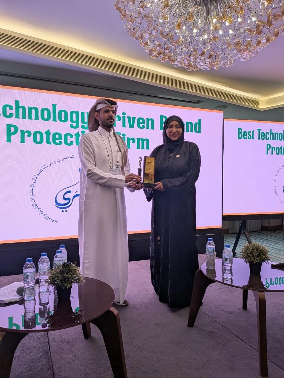 An award recipient and presenter holding a trophy at a past IIPLA ceremony.